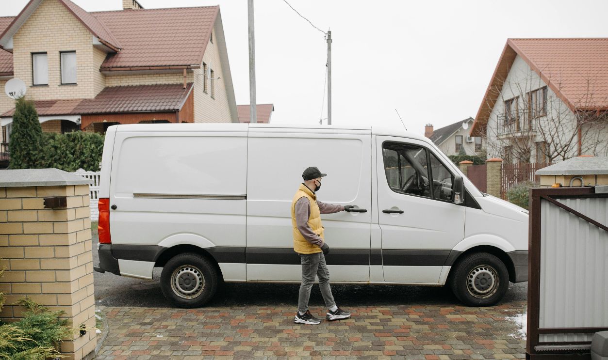 A delivery man exits his van in a suburban residential neighborhood