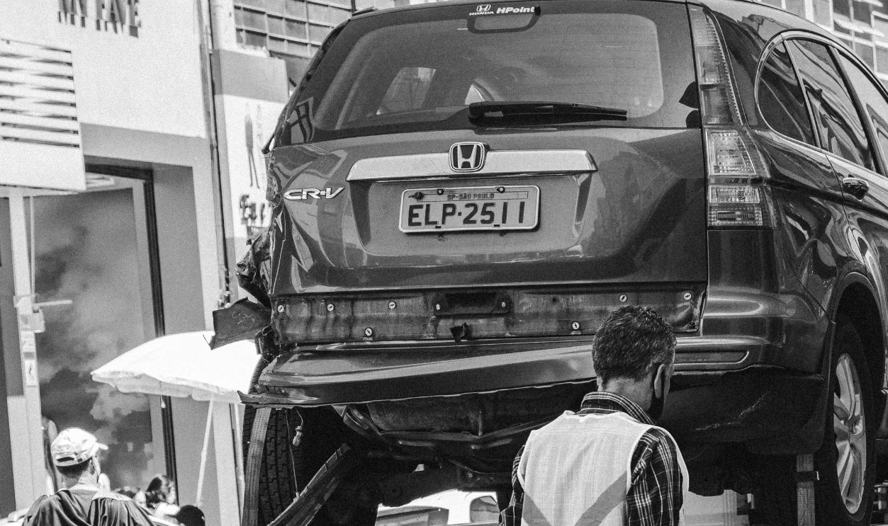 Grayscale image of a tow truck loading a vehicle on a busy street