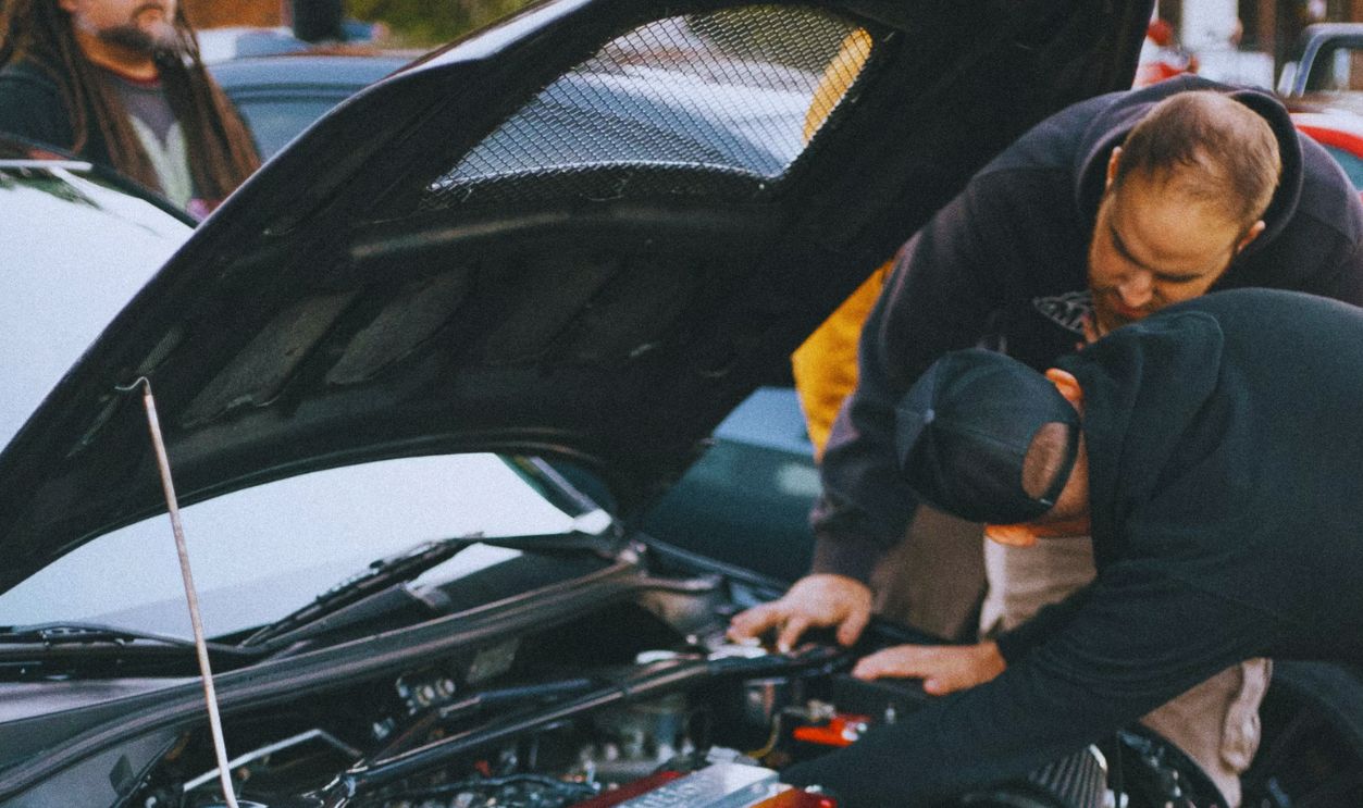 man in black jacket standing beside black car