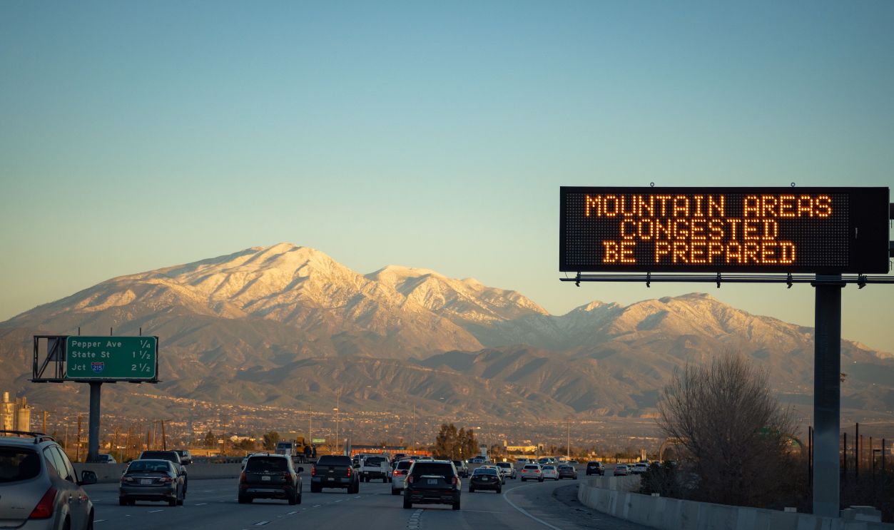 Traffic on a California highway with mountain view and LED display warning. Ideal for travel and commuter themes
