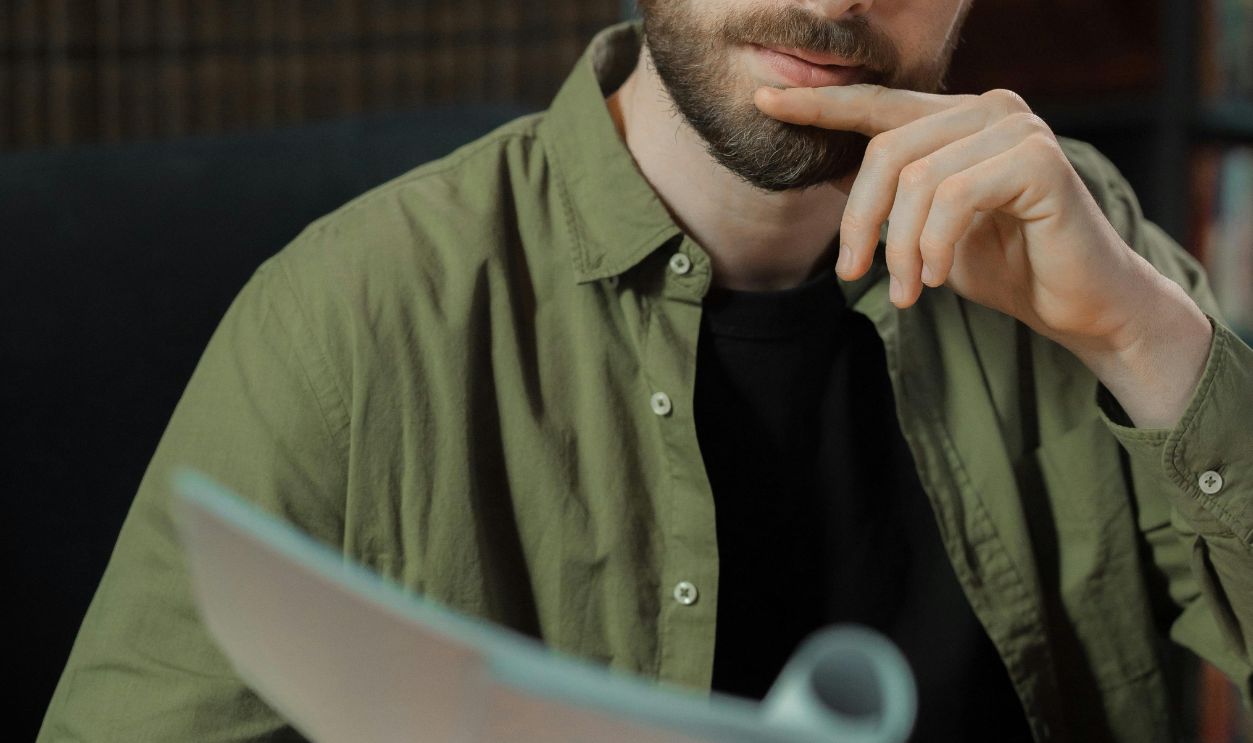 A focused writer in a library reviewing documents, deep in thought