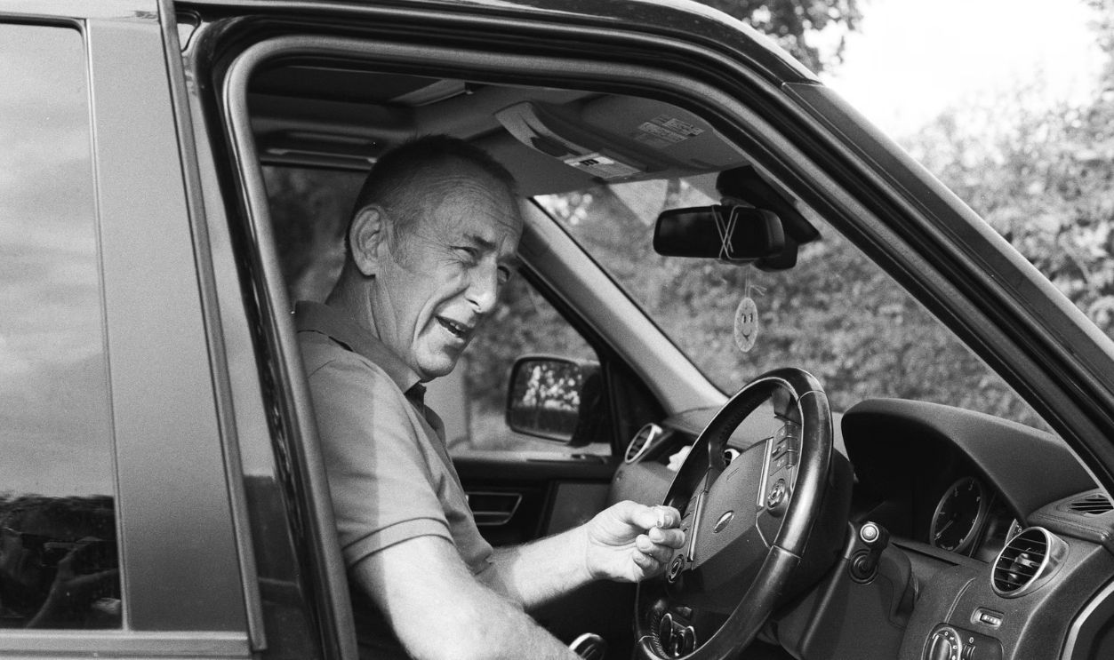 man in gray polo shirt driving car