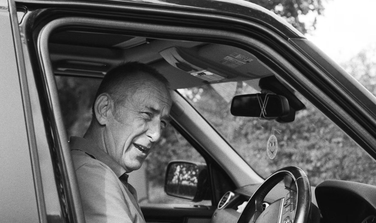 man in gray polo shirt driving car