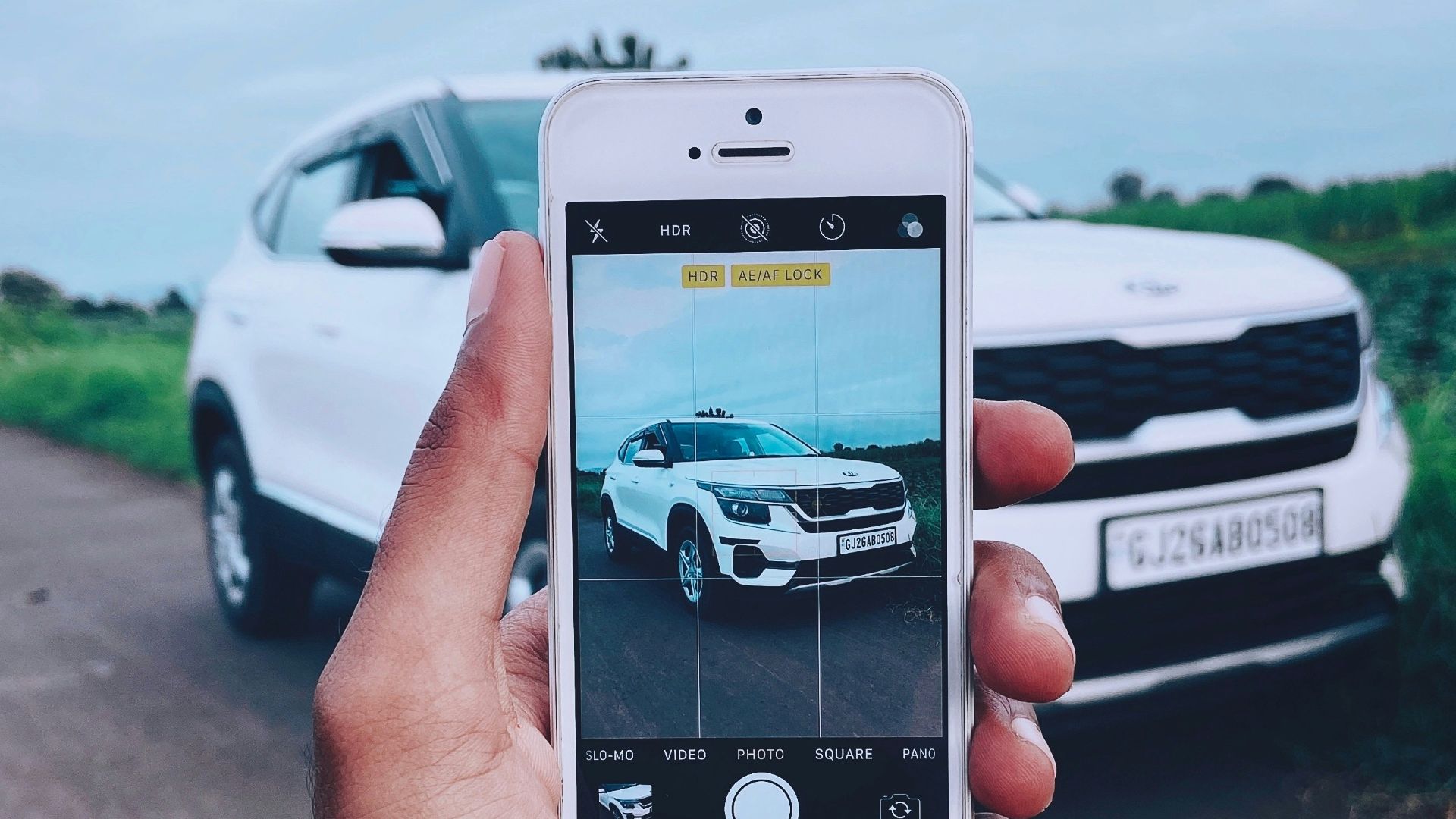 person holding silver iphone 6 taking photo of white car on road during daytime