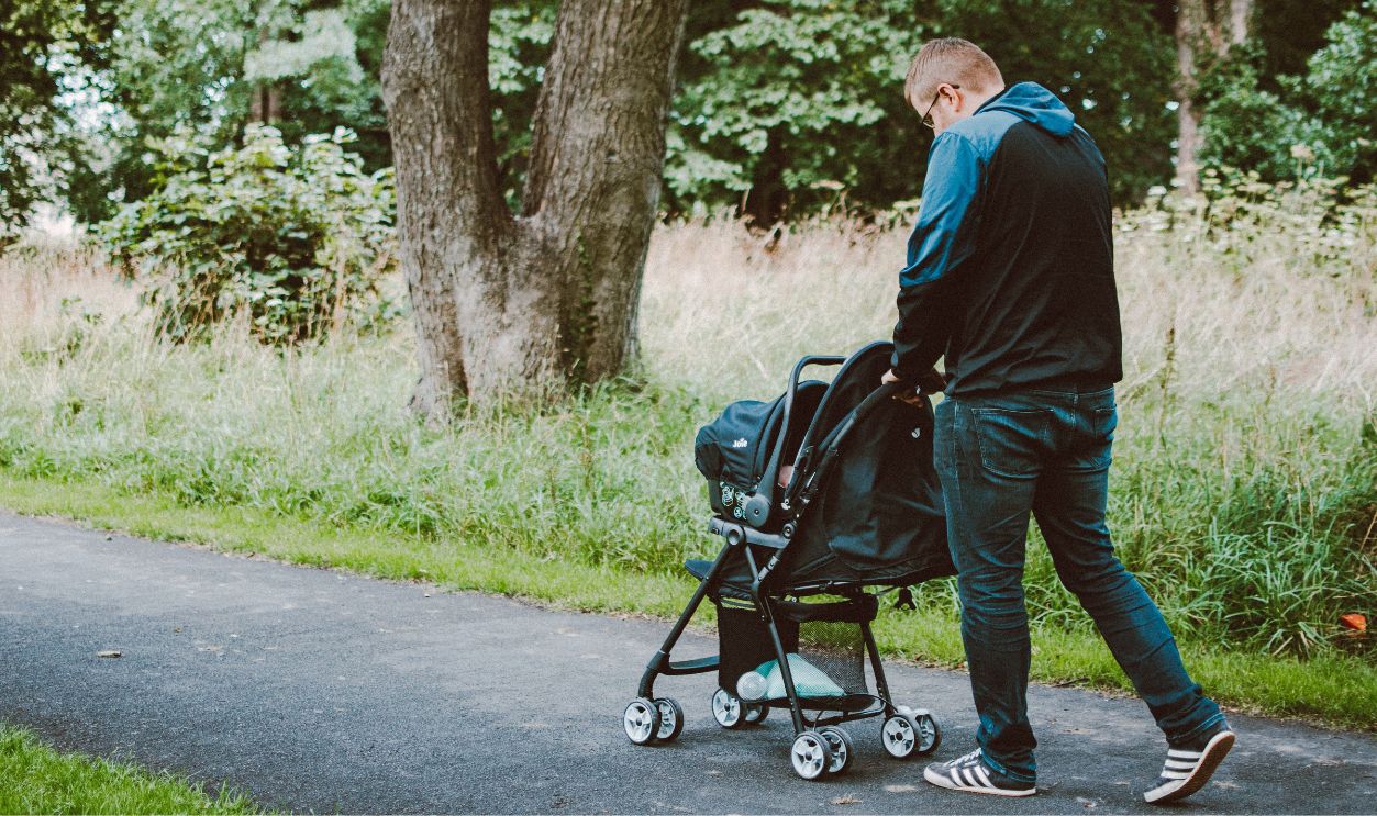 A father pushing a stroller on a park pathway