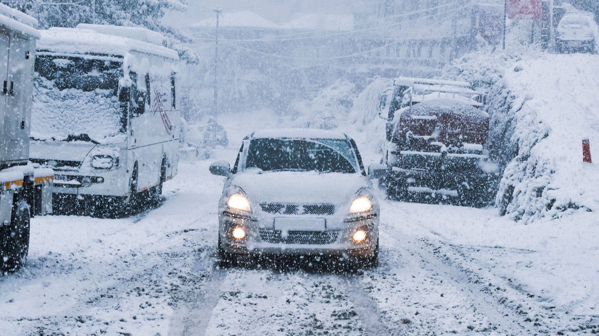 A snowy city street scene featuring cars and heavy snowfall, capturing urban winter transportation.