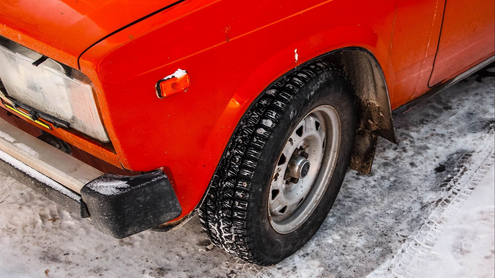 Close-up of a vintage car on snow-covered ground showcasing icy winter conditions.