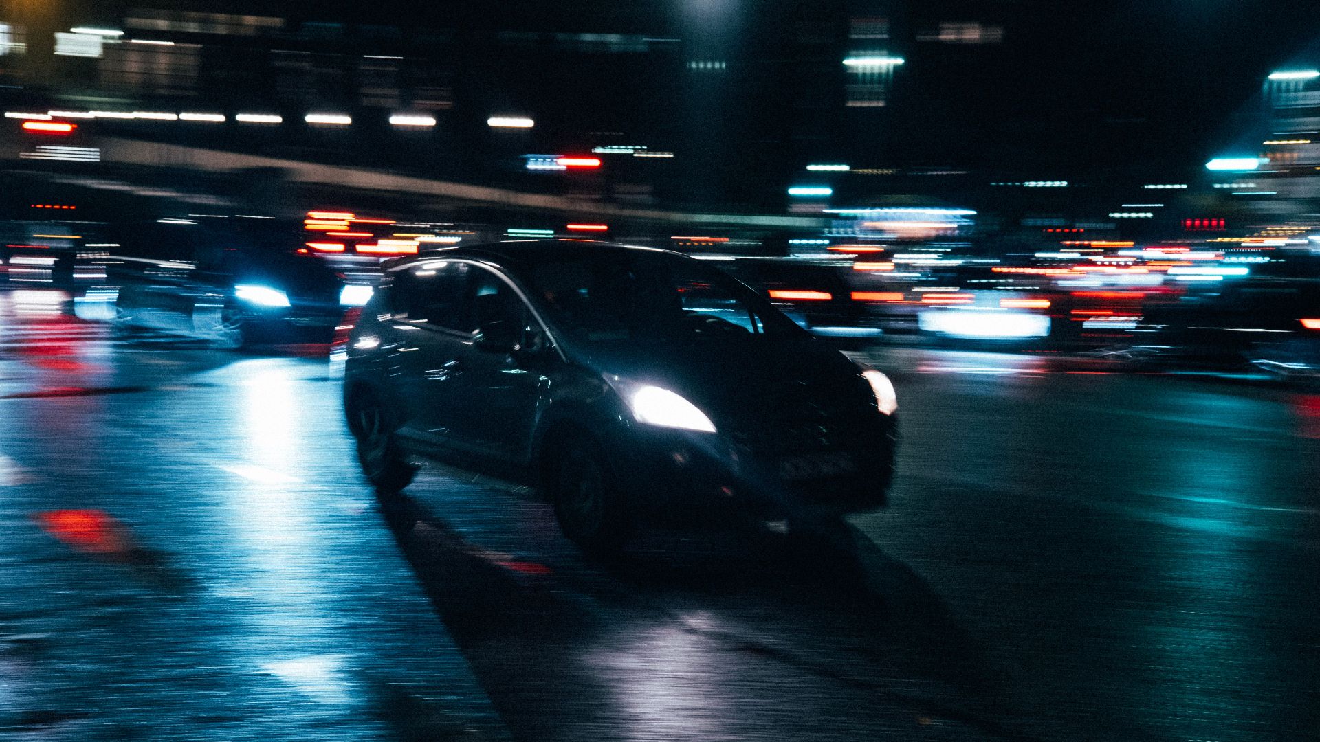 Blurred cars and city lights create a dynamic nighttime urban scene, showcasing motion and energy.