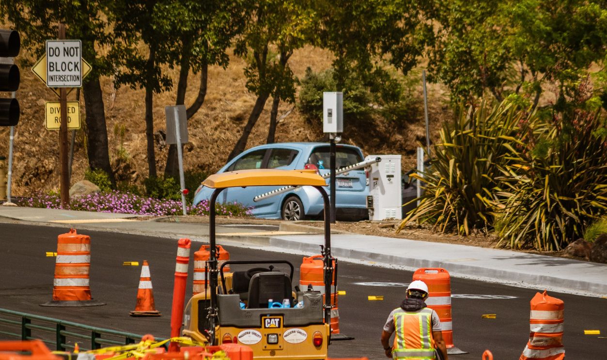 A road construction worker surrounded by safety cones on a street