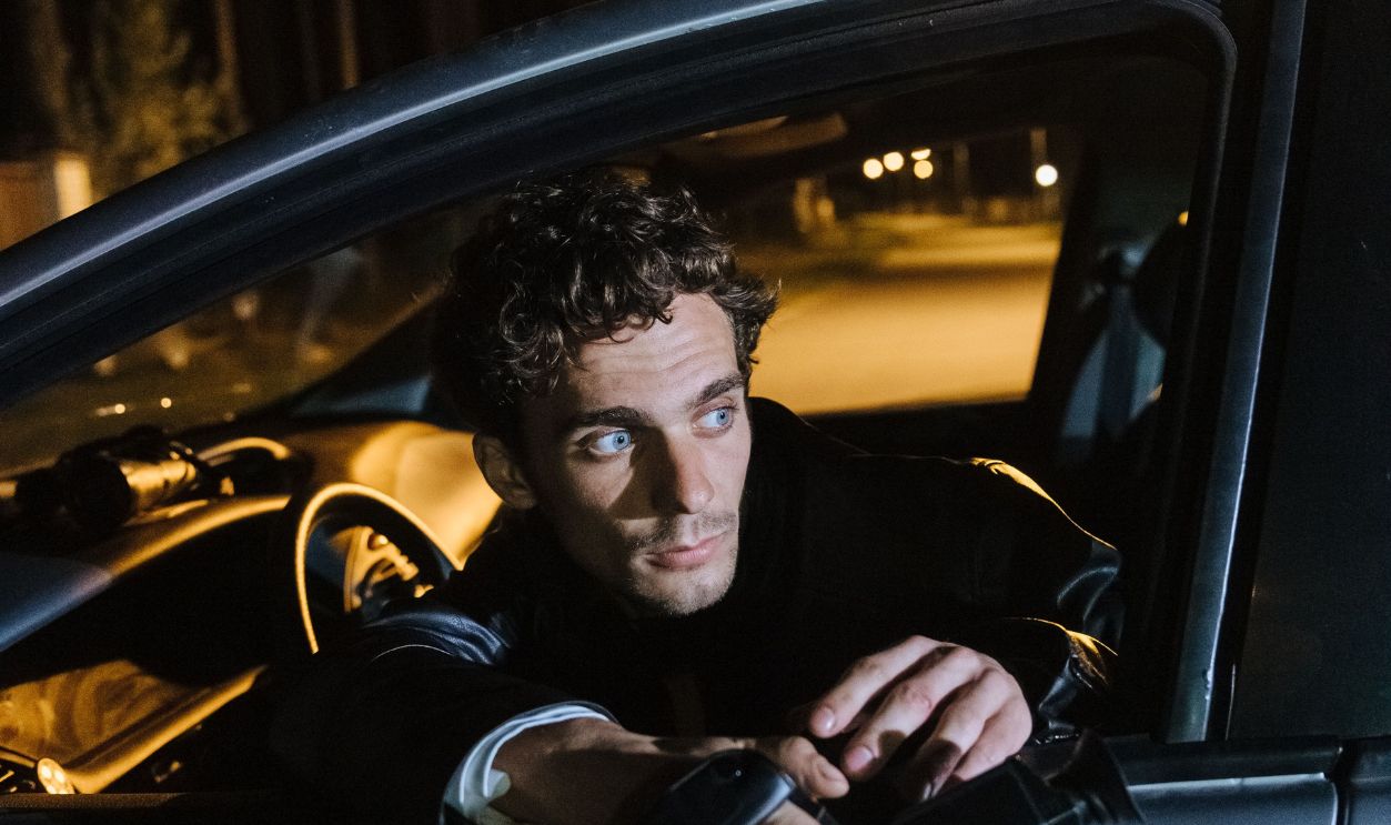 Man sits in car at night holding a mysterious object