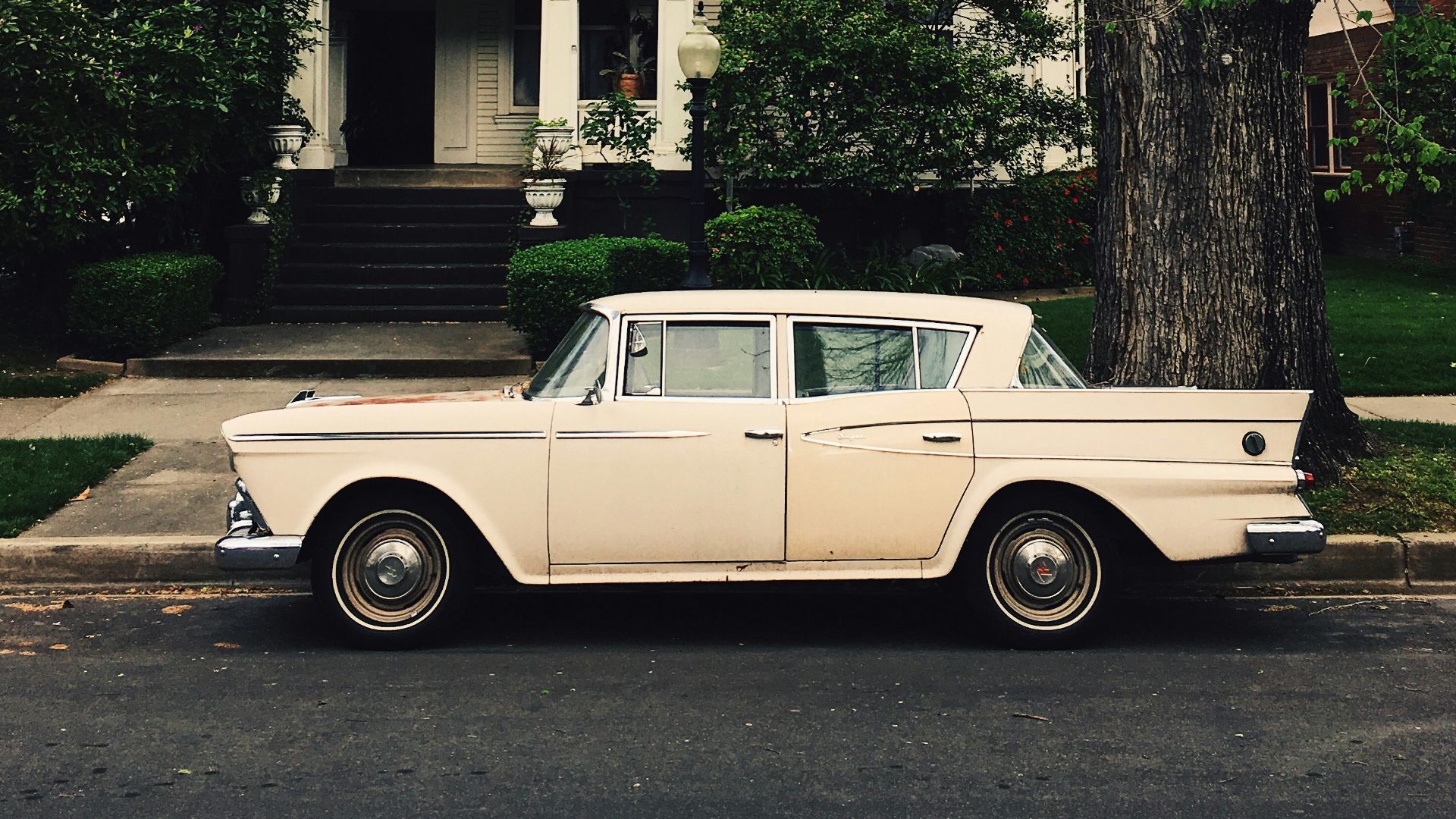 white sedan parked in front of house near tree