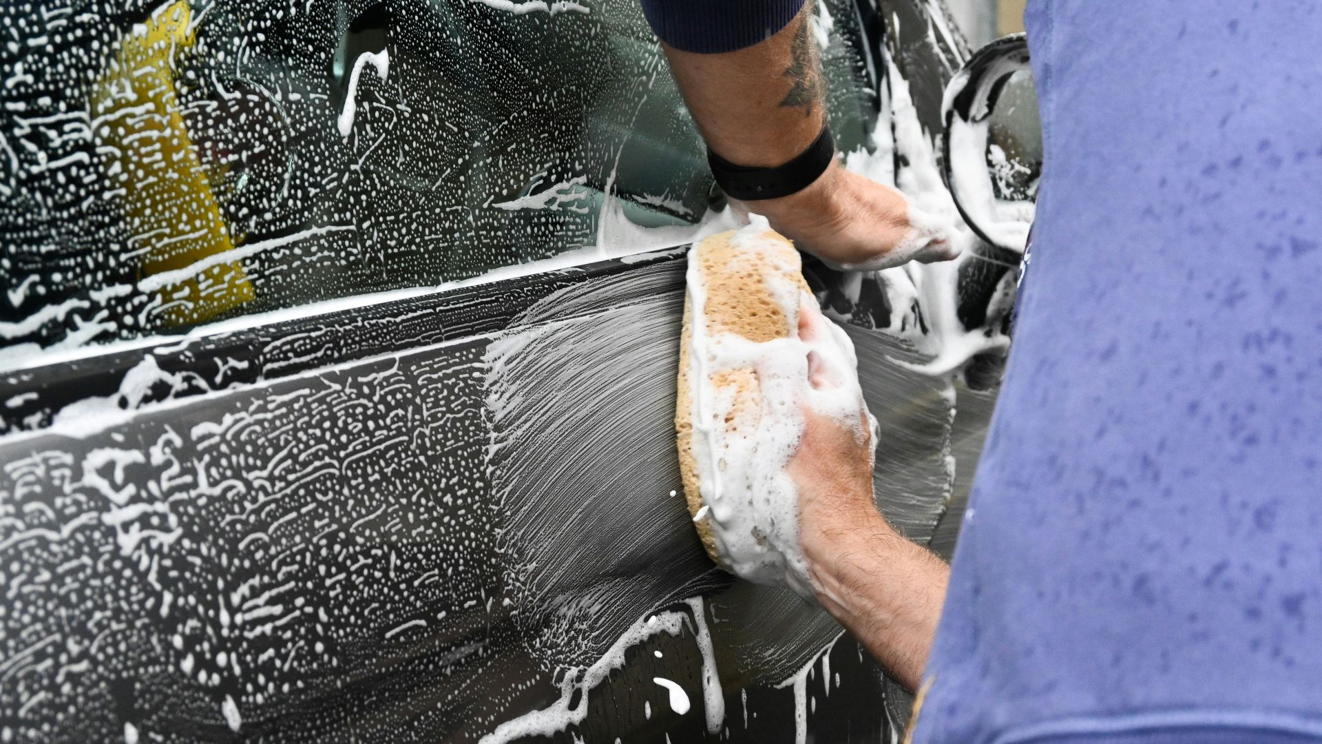 a man washing a car with a sponge