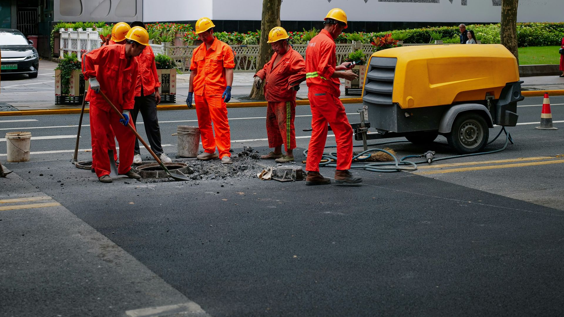 a group of men in orange work on a street