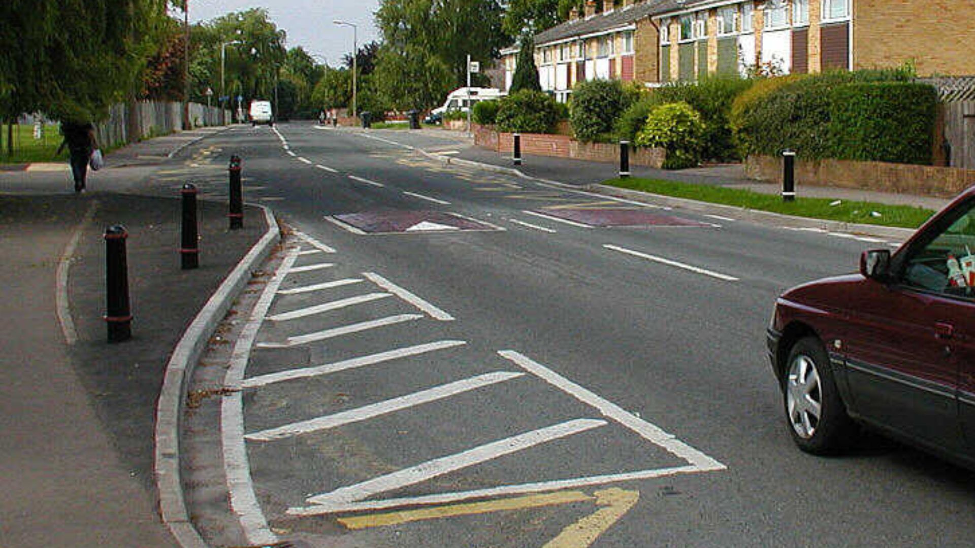 Traffic calming measures (road narrowing and speed bumps) in Yate, near Bristol, England.
The speed bumps are reddish, and the narrowed area is blacker than the old pavement.

Taken by Adrian Pingstone and released to the public domain.