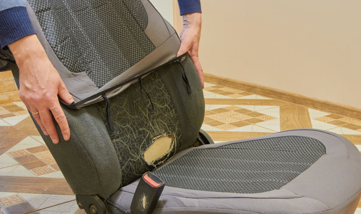 an old torn car seat, a man puts on a new fabric cover