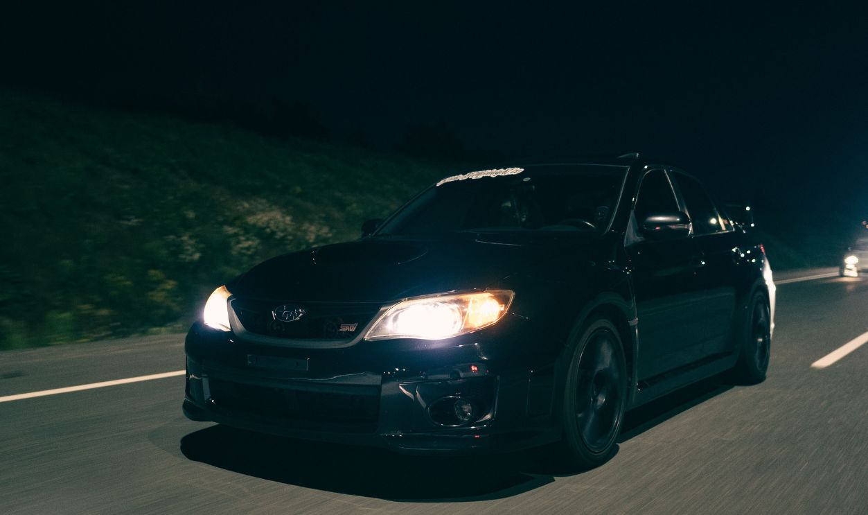 Black car speeding on a highway at night
