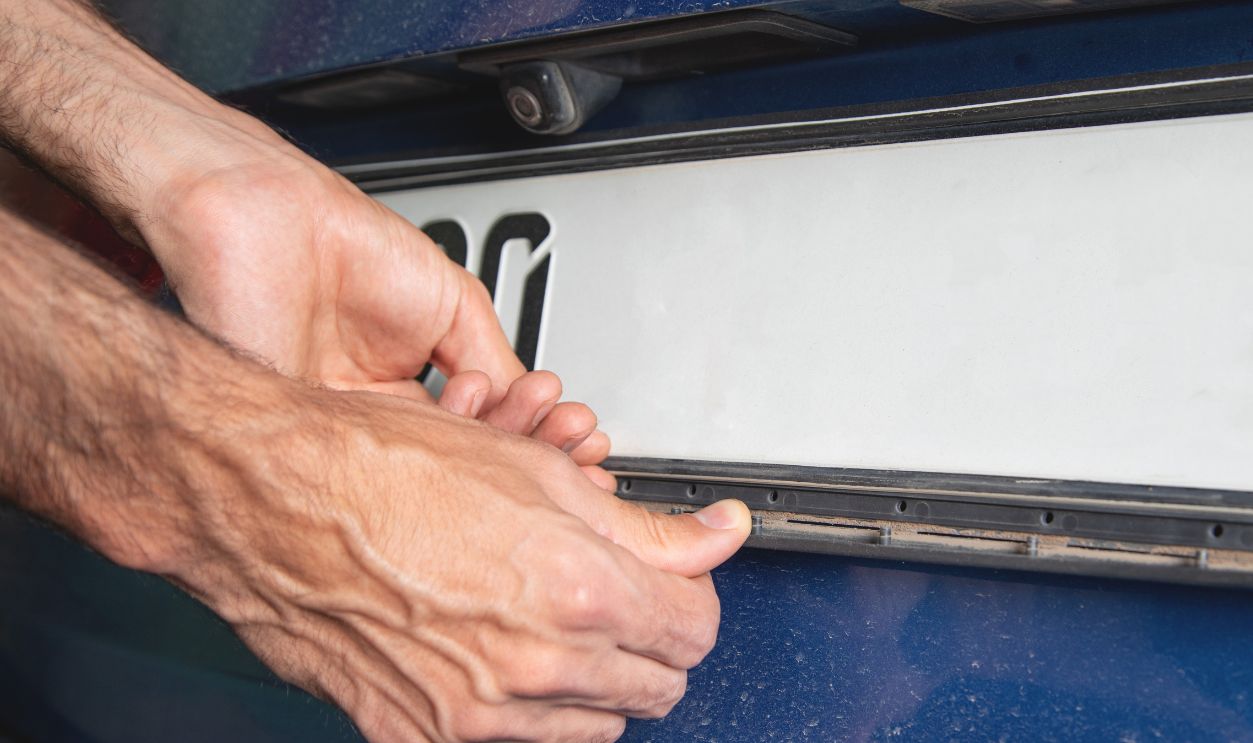 Caucasian man changing car number. Transport