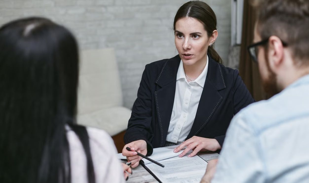Three colleagues engaged in a business meeting discussing documents at a table indoors
