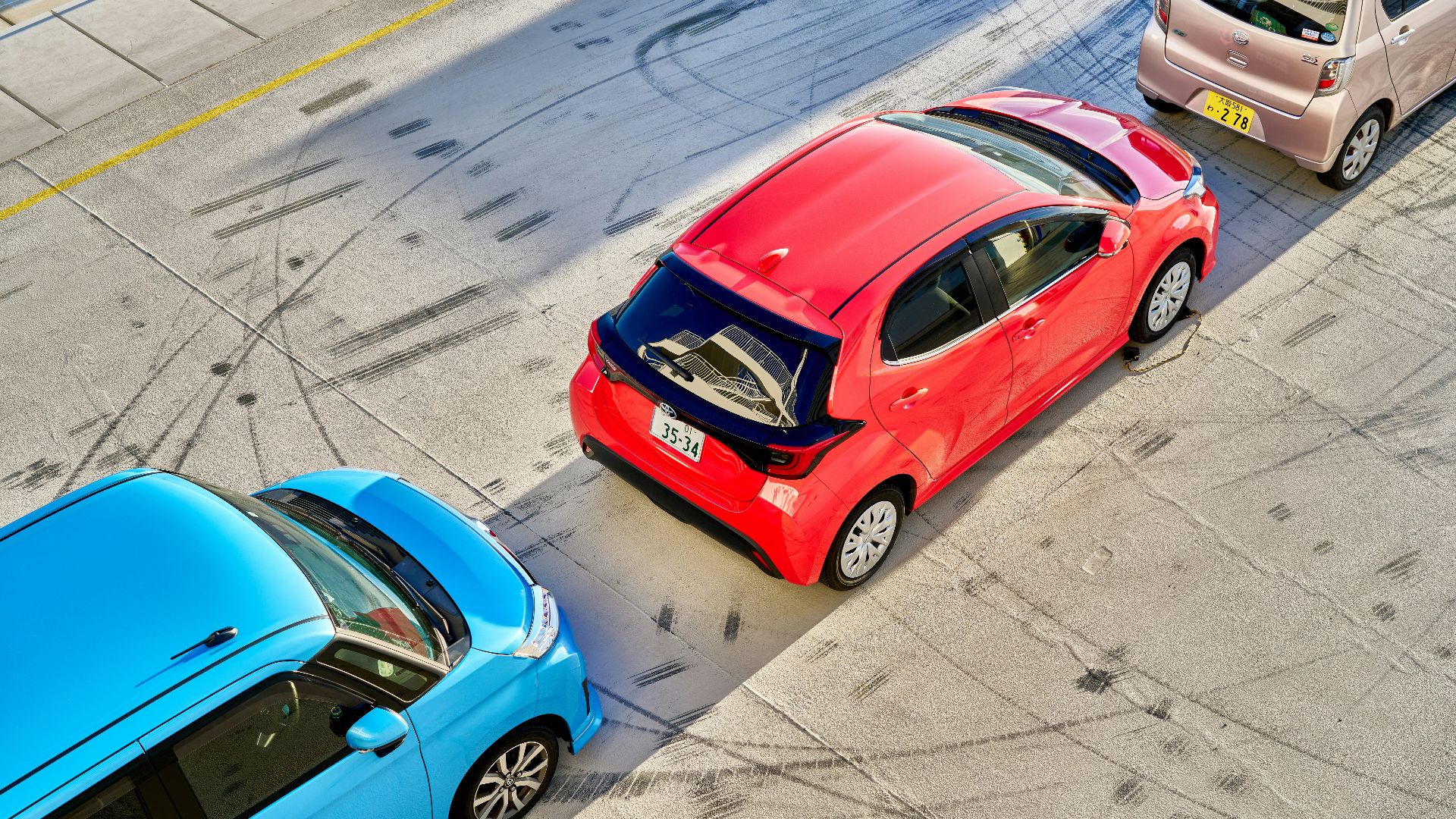 Three different colored cars driving down a street