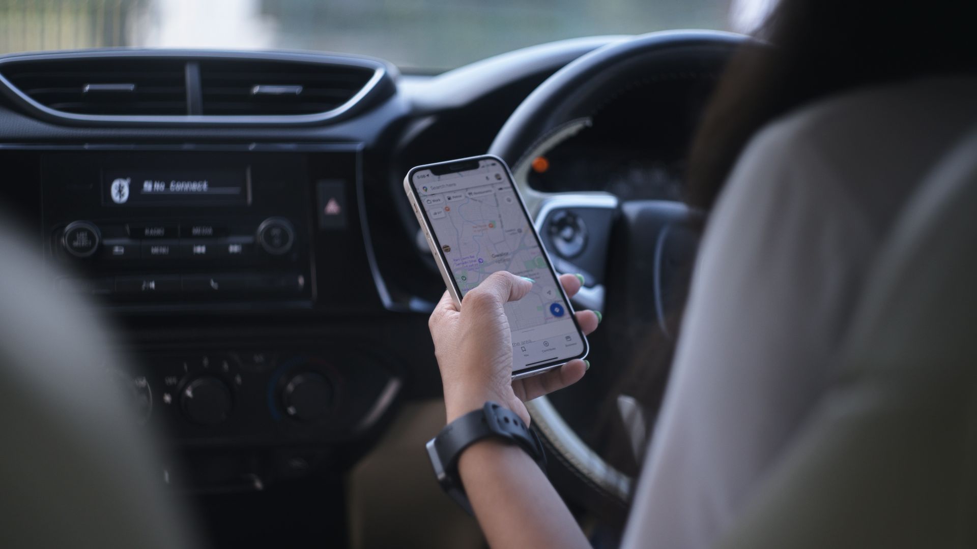 A woman holding a cell phone while driving a car