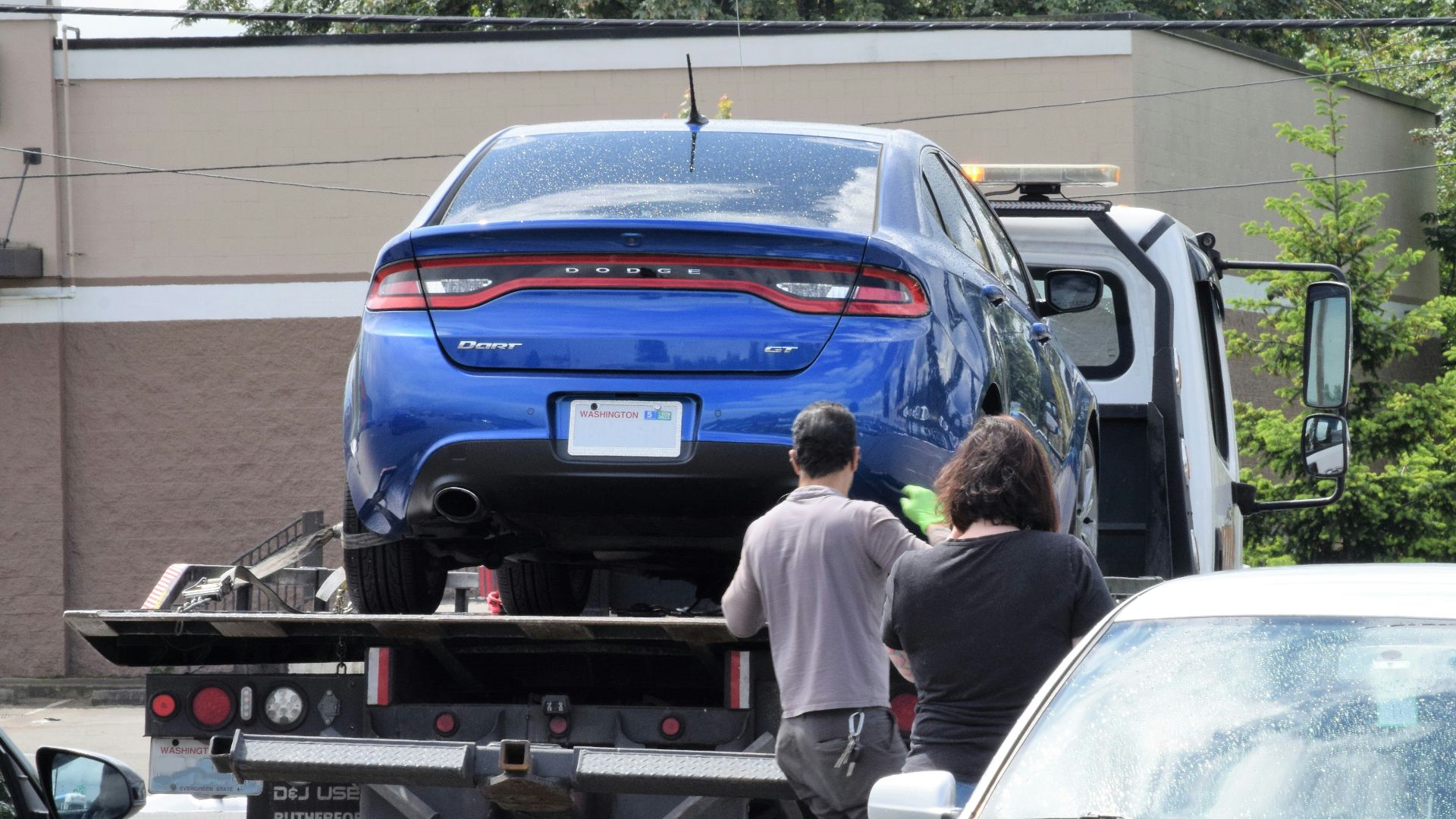 a blue car being loaded onto a flatbed truck