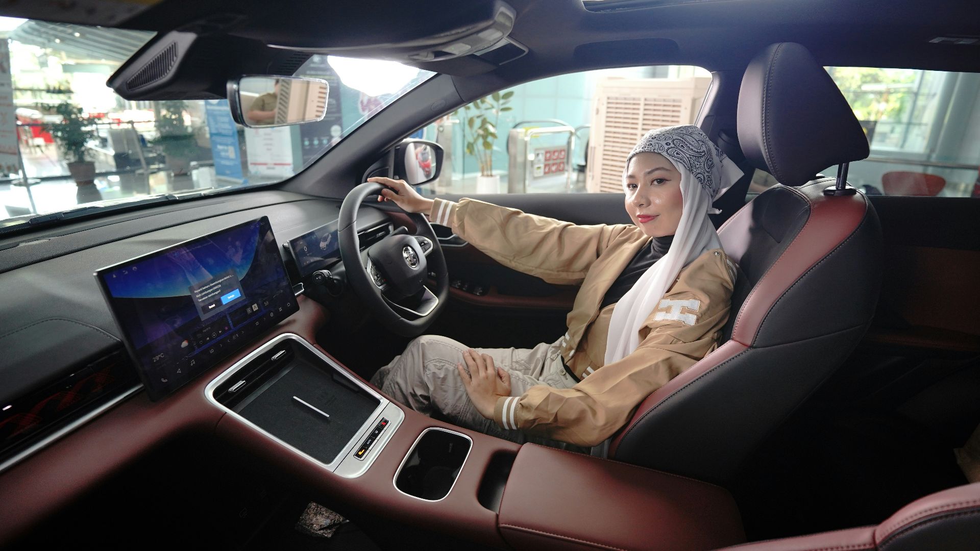Woman smiles while sitting inside of a car.