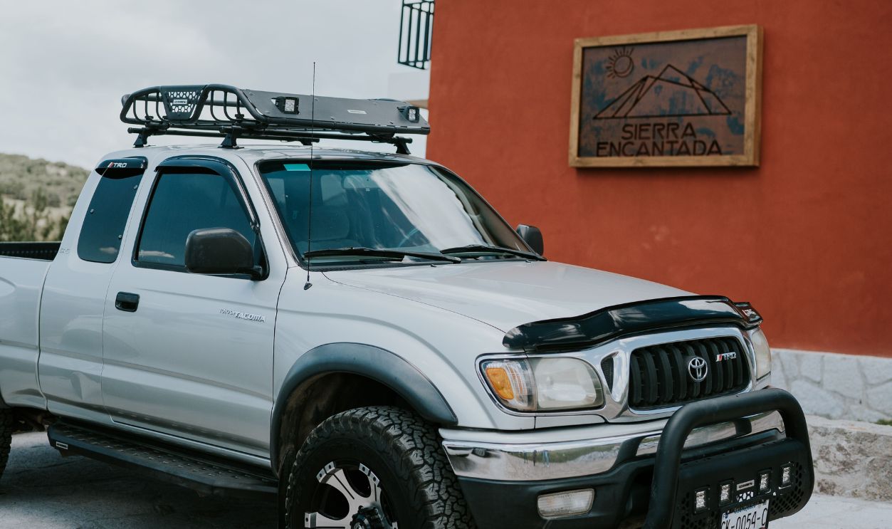 Silver Toyota pickup truck parked beside a red building under a clear sky