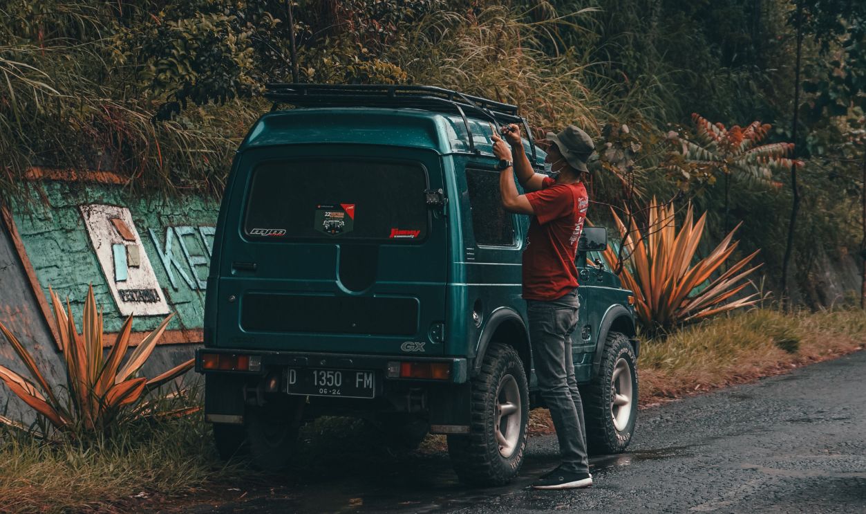 A man standing next to an SUV adjusting the roof rack