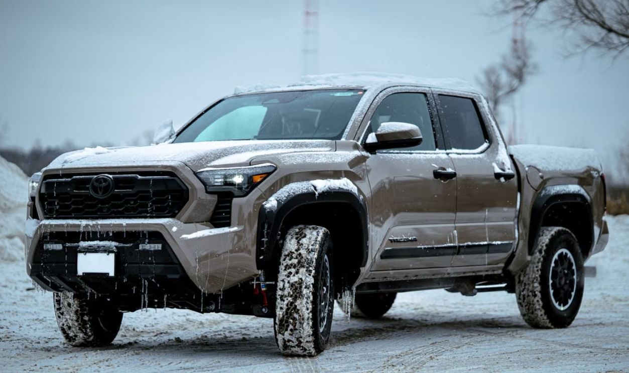 Brown pickup truck covered in snow parked outdoors in a winter setting