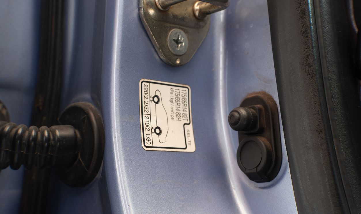 Vehicle door jamb with tire pressure information sticker displaying recommended tire specifications.