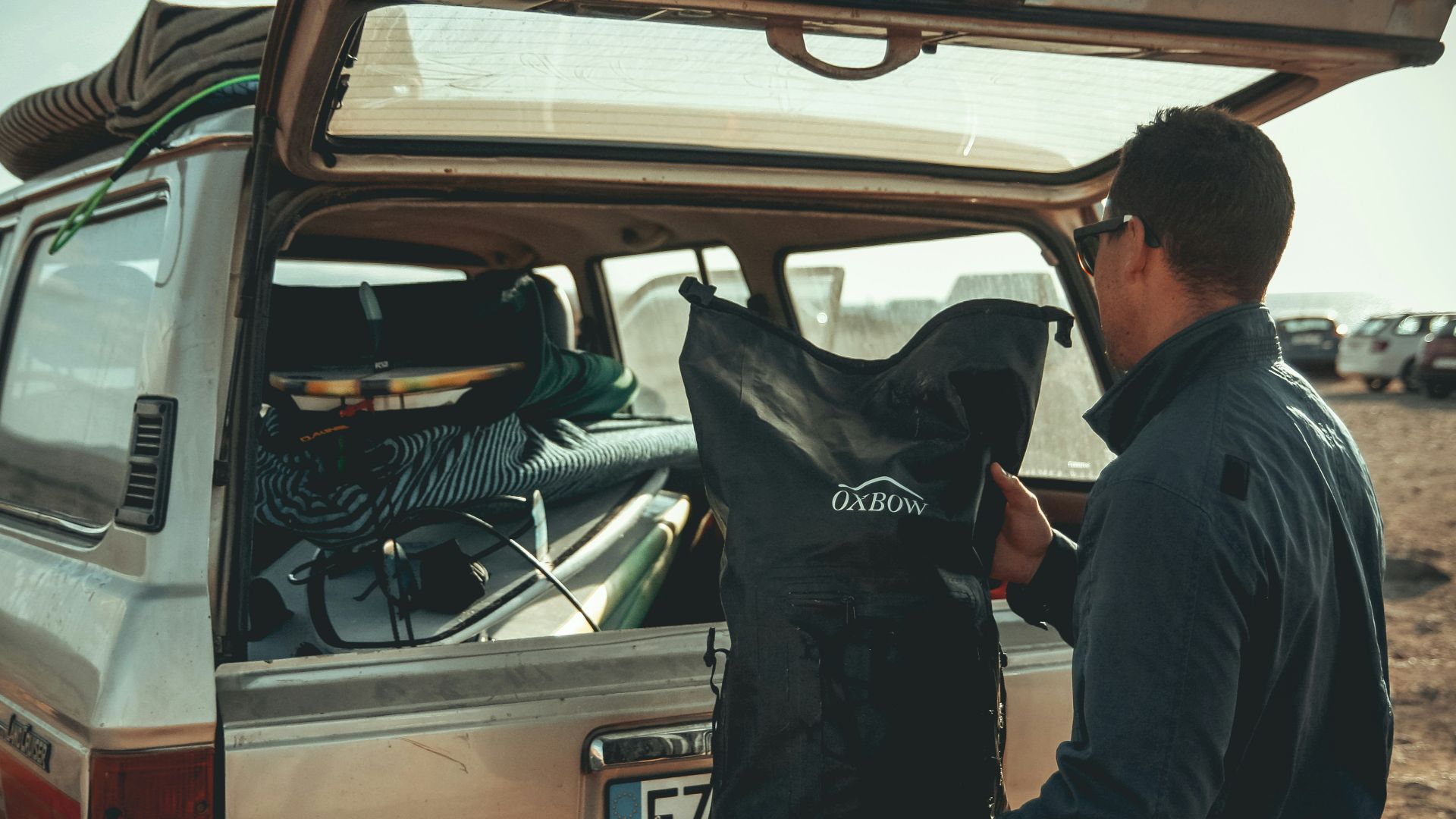 man loading black bag in back of suv