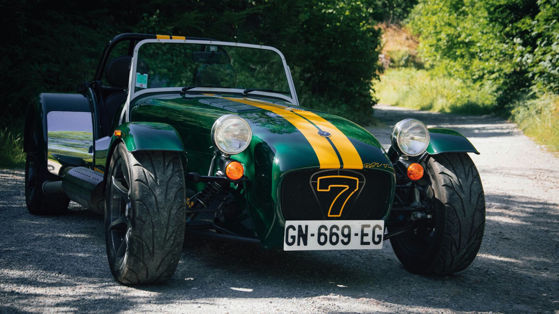 a green and yellow car parked on a gravel road