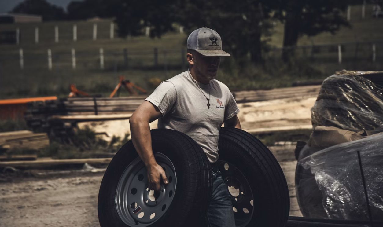 man carrying two vehicle wheels