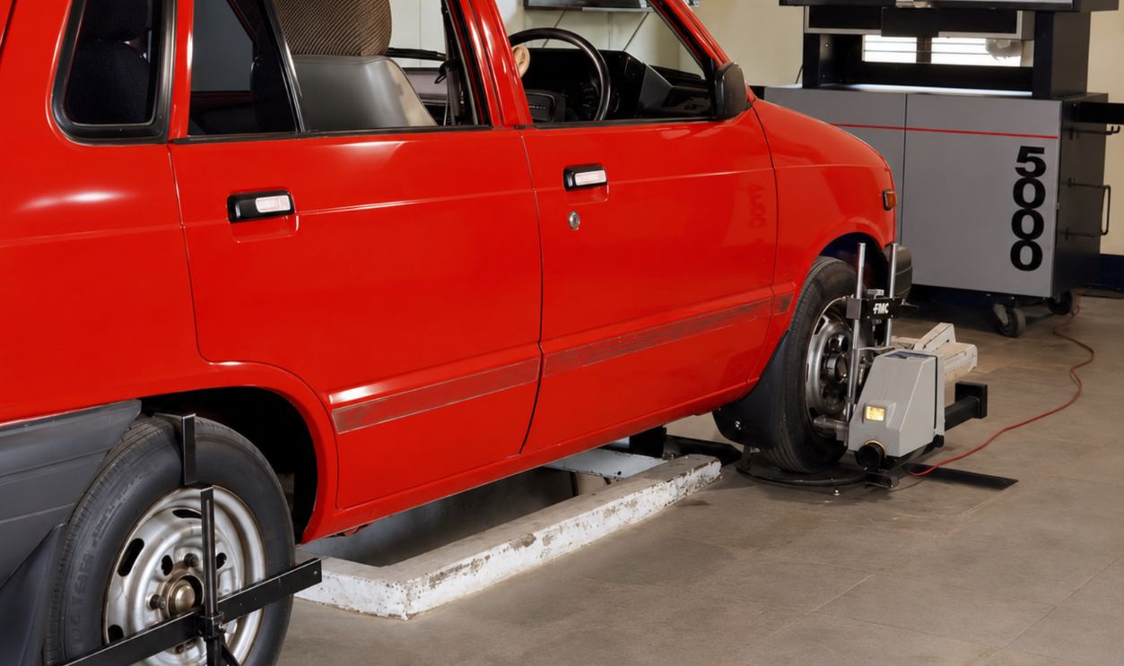 Red compact car in an automotive workshop undergoing computerized wheel alignment service