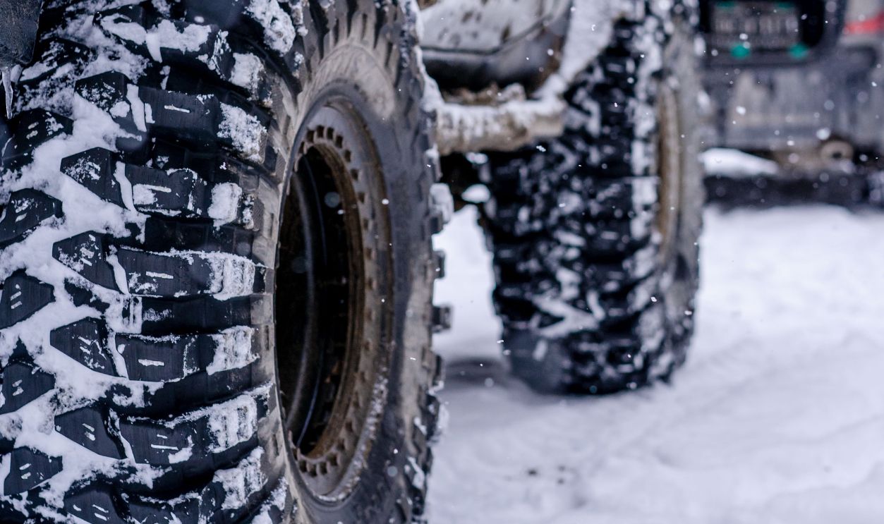Close-up of rugged off-road jeep tires in a snowy winter setting, highlighting traction and adventure