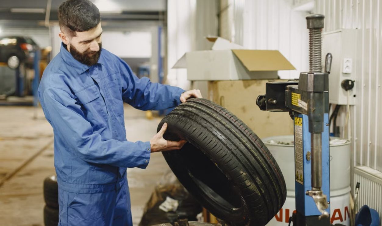 Mechanic in blue uniform examining a tire in an automotive garage