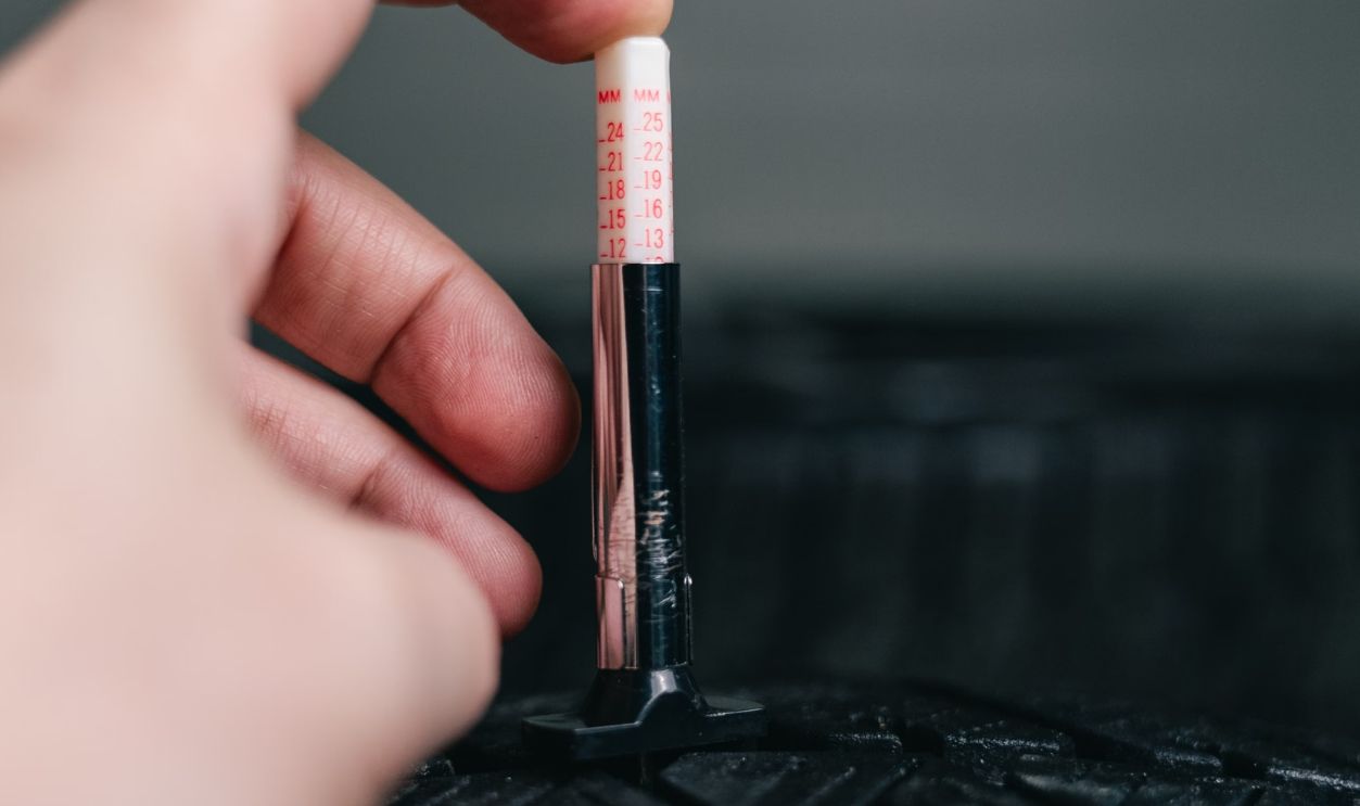Close-up of hand using a tread depth gauge on a tire. Safety and maintenance check