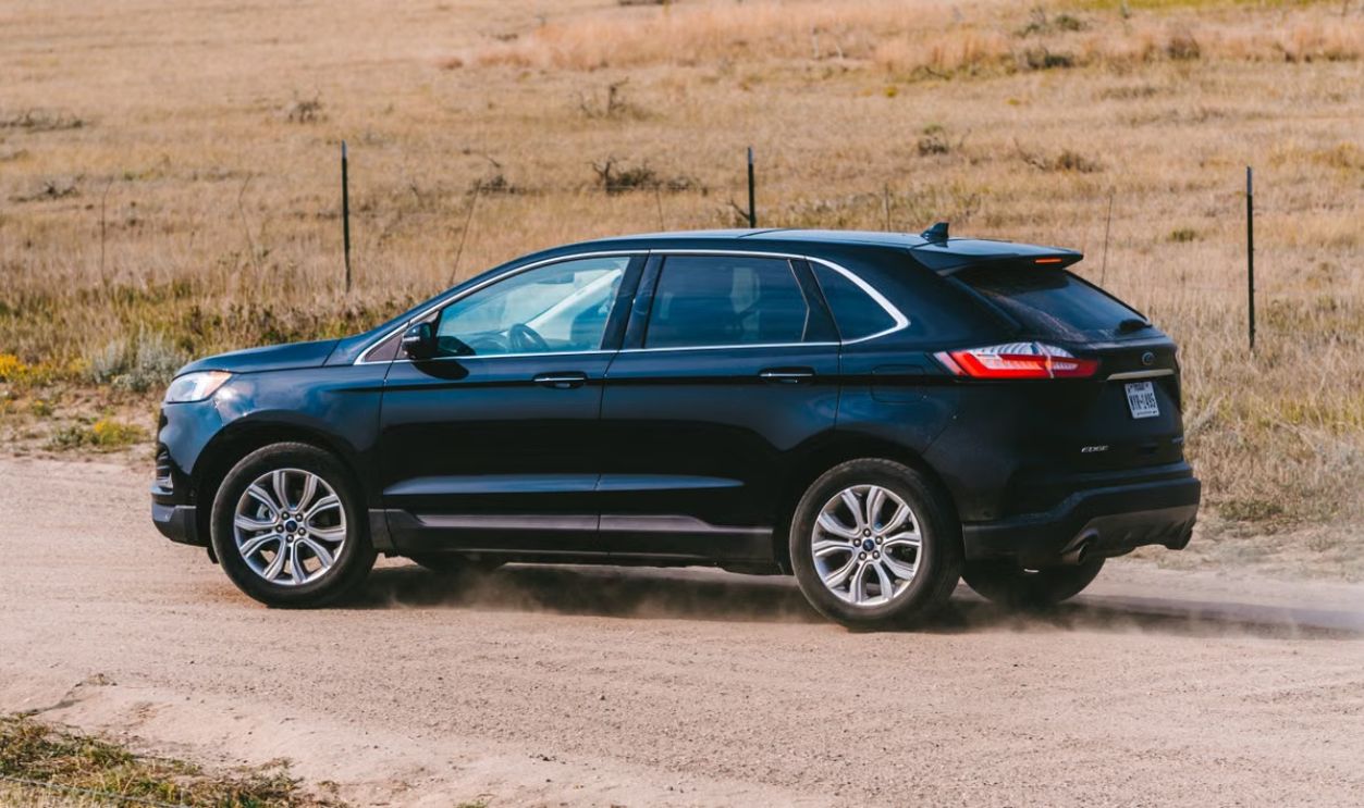 A black SUV travels on a dusty rural road, showcasing motion and adventure