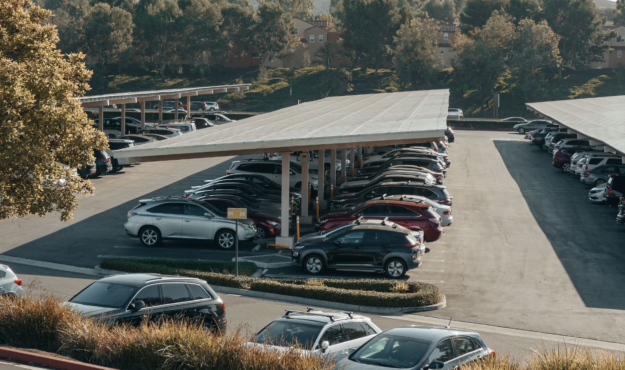 View of a large parking lot with solar panel shades and diverse vehicles