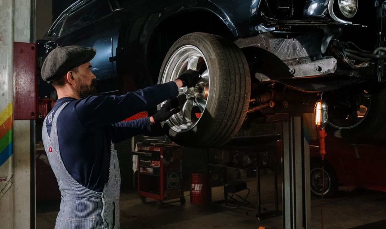 A focused mechanic works on a car wheel in a dimly lit garage, showcasing automotive repair skills