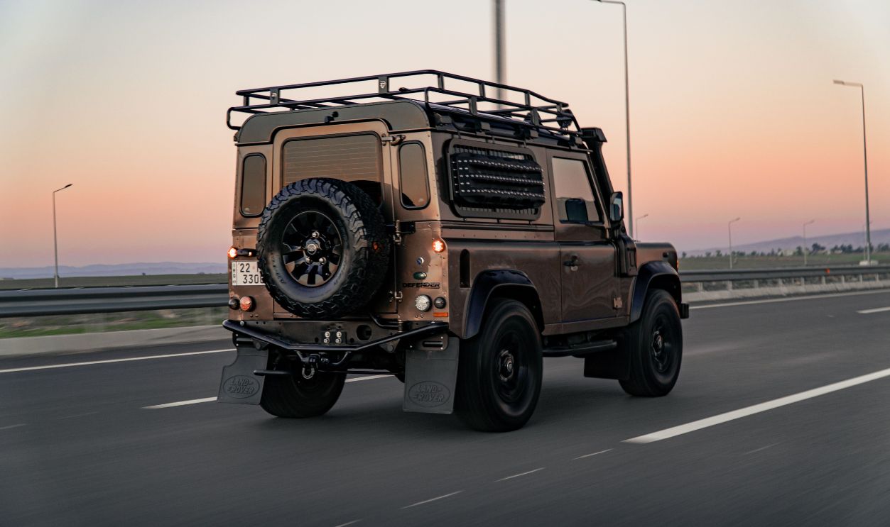 A Land Rover Defender SUV drives on a highway