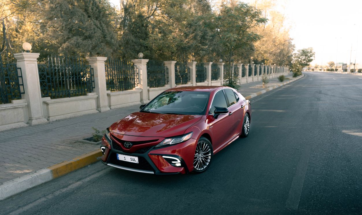 Red Toyota sedan parked near a stylish urban street, showcasing sleek design and elegance