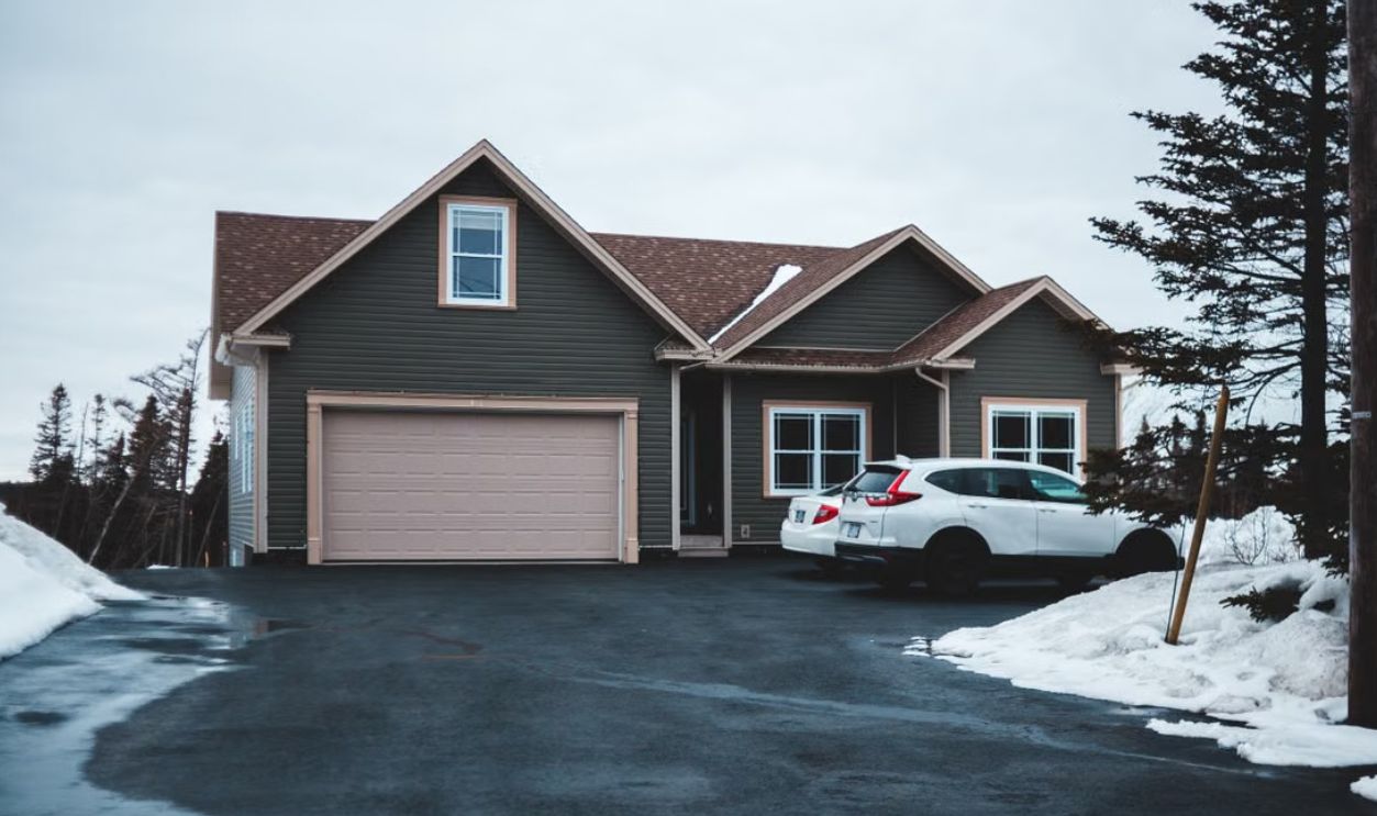 A suburban house with snow-covered surroundings and a parked car during winter