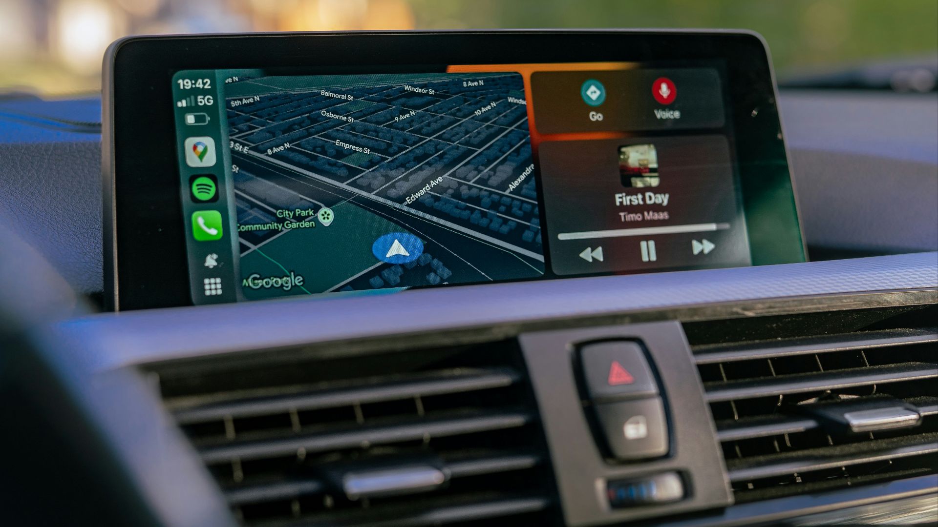Car dashboard displaying navigation and music apps.