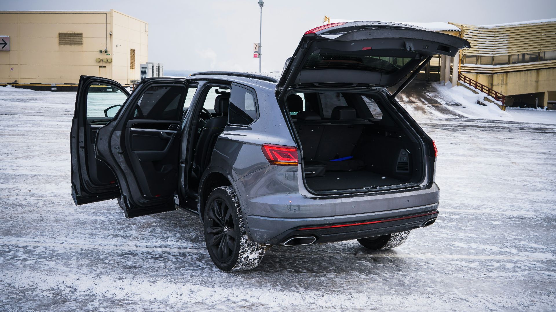 Gray suv with open doors and trunk in snow.