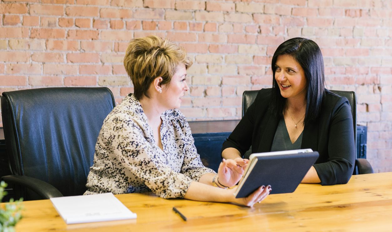 Two women sitting on leather chairs in office