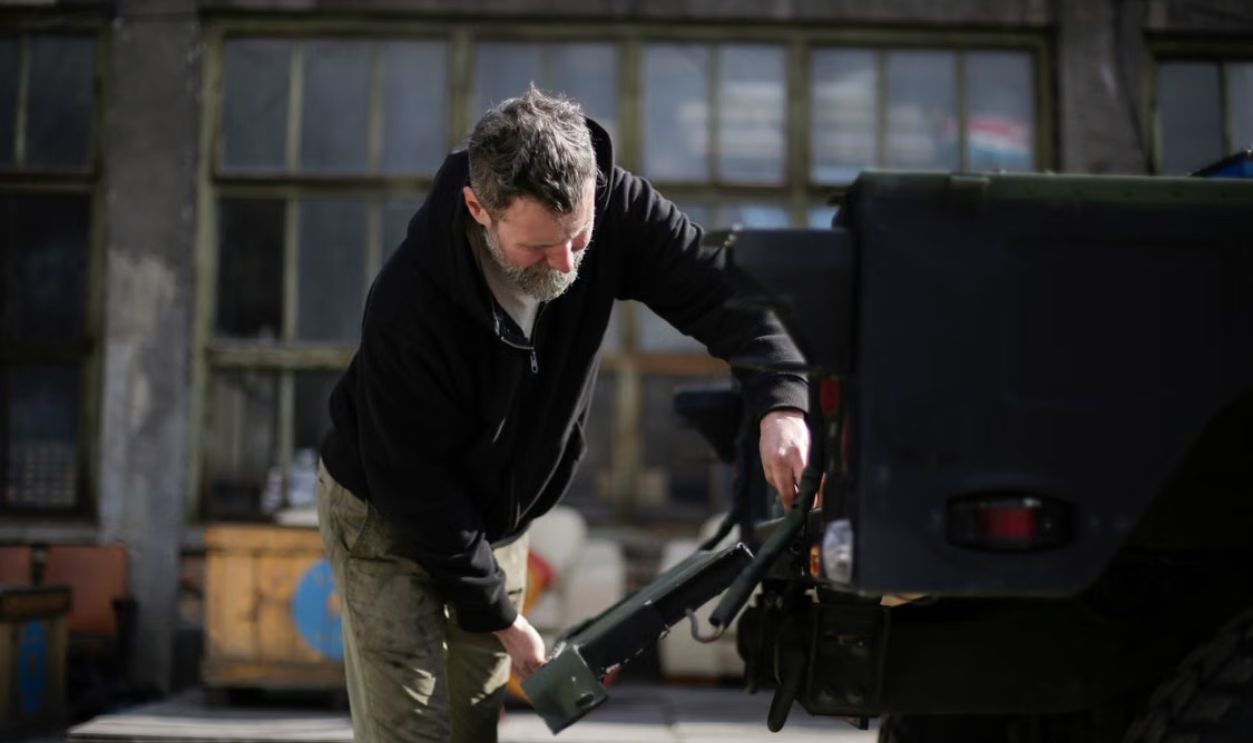 A mechanic working on a vehicle outdoors, showcasing automotive repair skills.