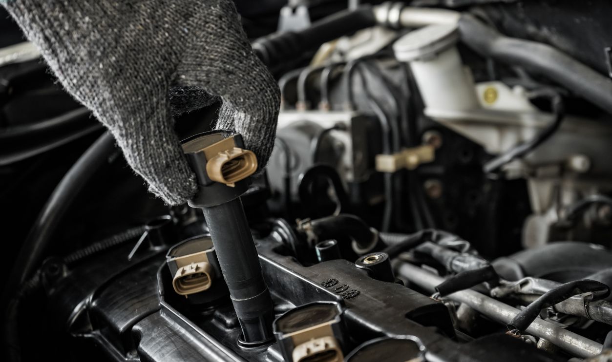 Close-up of mechanic's hand removing ignition coil or spark plug coil to check or replace for vehicle maintenance, repair and maintenance concept.