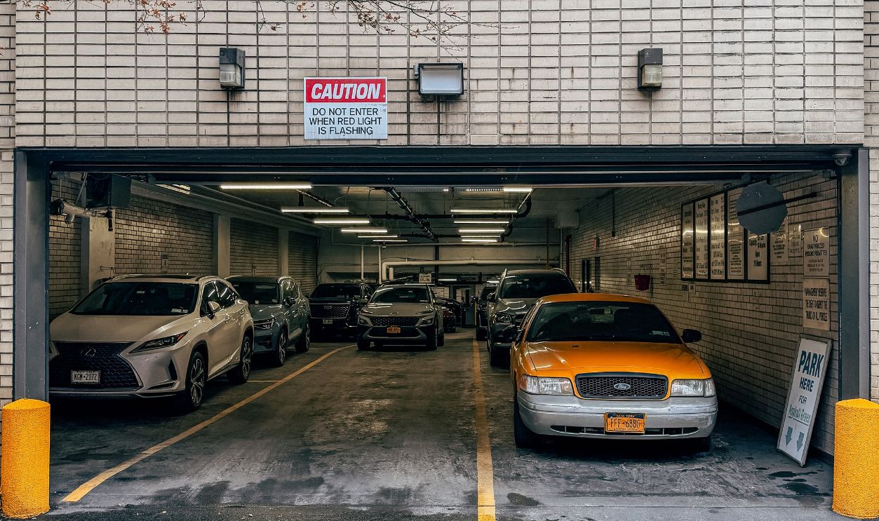 A parking garage in New York City featuring parked cars, including a yellow cab
