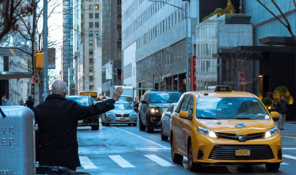 A man hailing a yellow taxi in bustling NYC street, capturing urban life